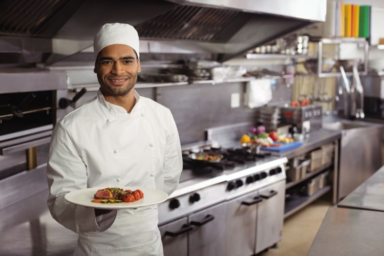 Portrait of smiling chef holding delicious dish in kitchen Portrait of smiling chef holding delicious dish in kitchen